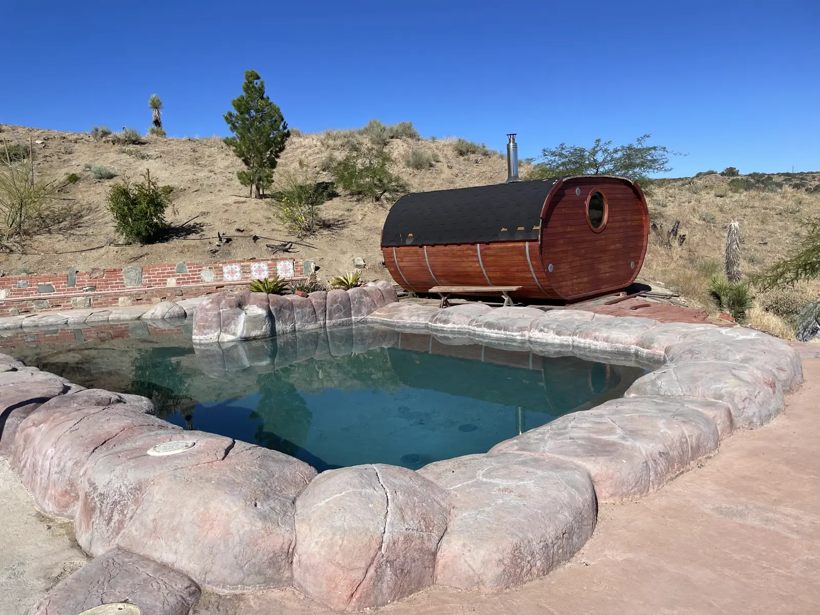 Natural rock-edged soaking pool with a cedar barrel sauna on the retreat property
