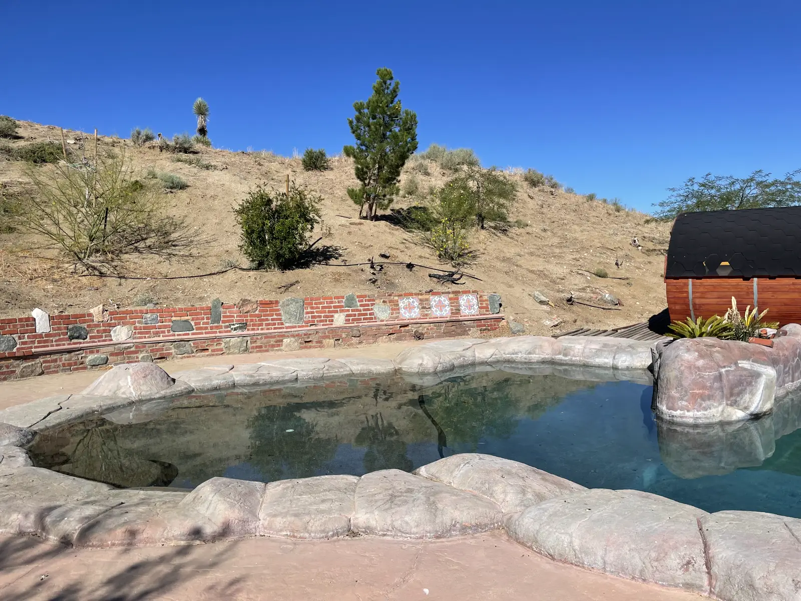 Wide view of the soaking pool framed by the desert hillside