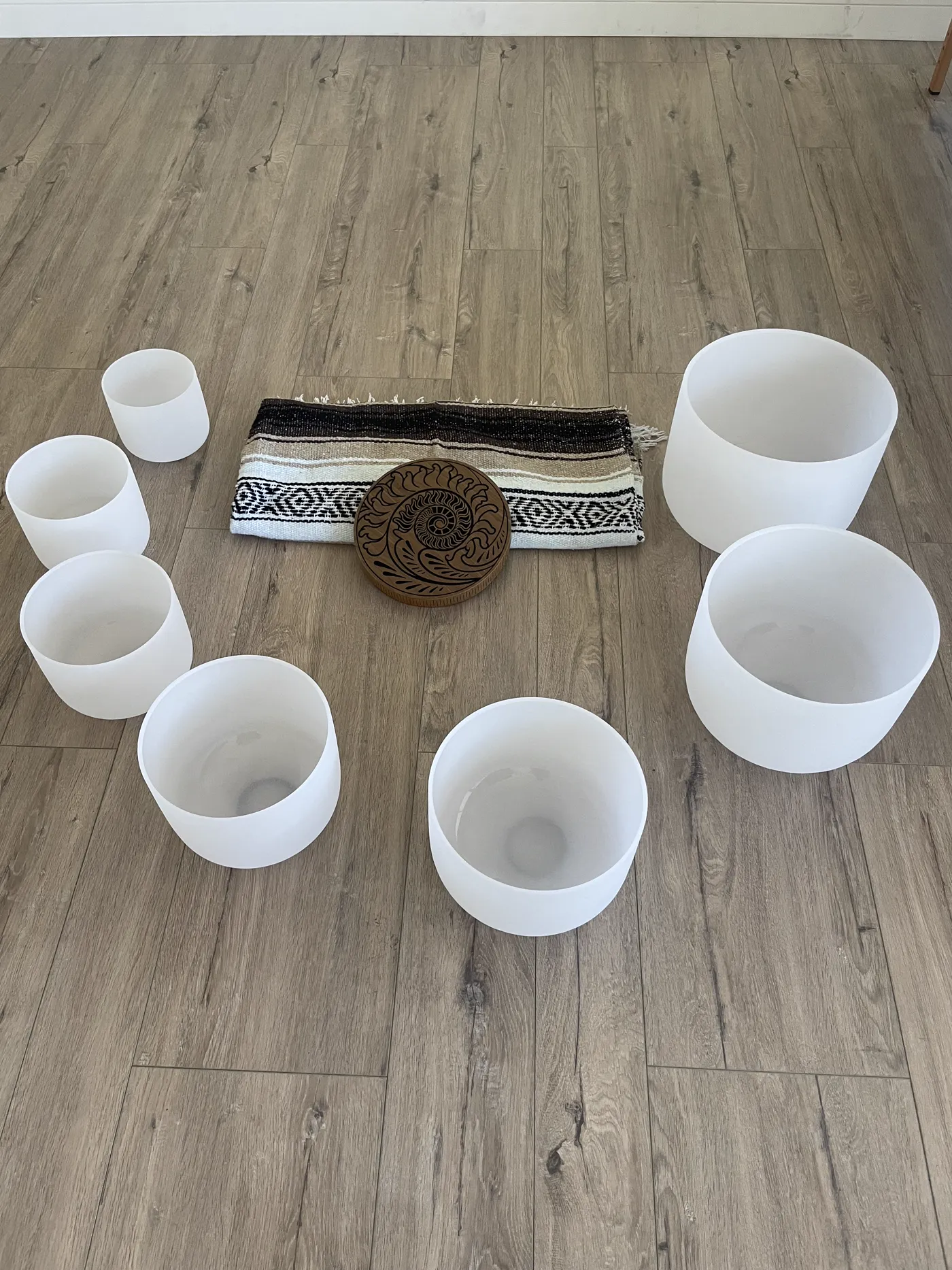 Crystal singing bowls and a woven blanket arranged for a sound bath session